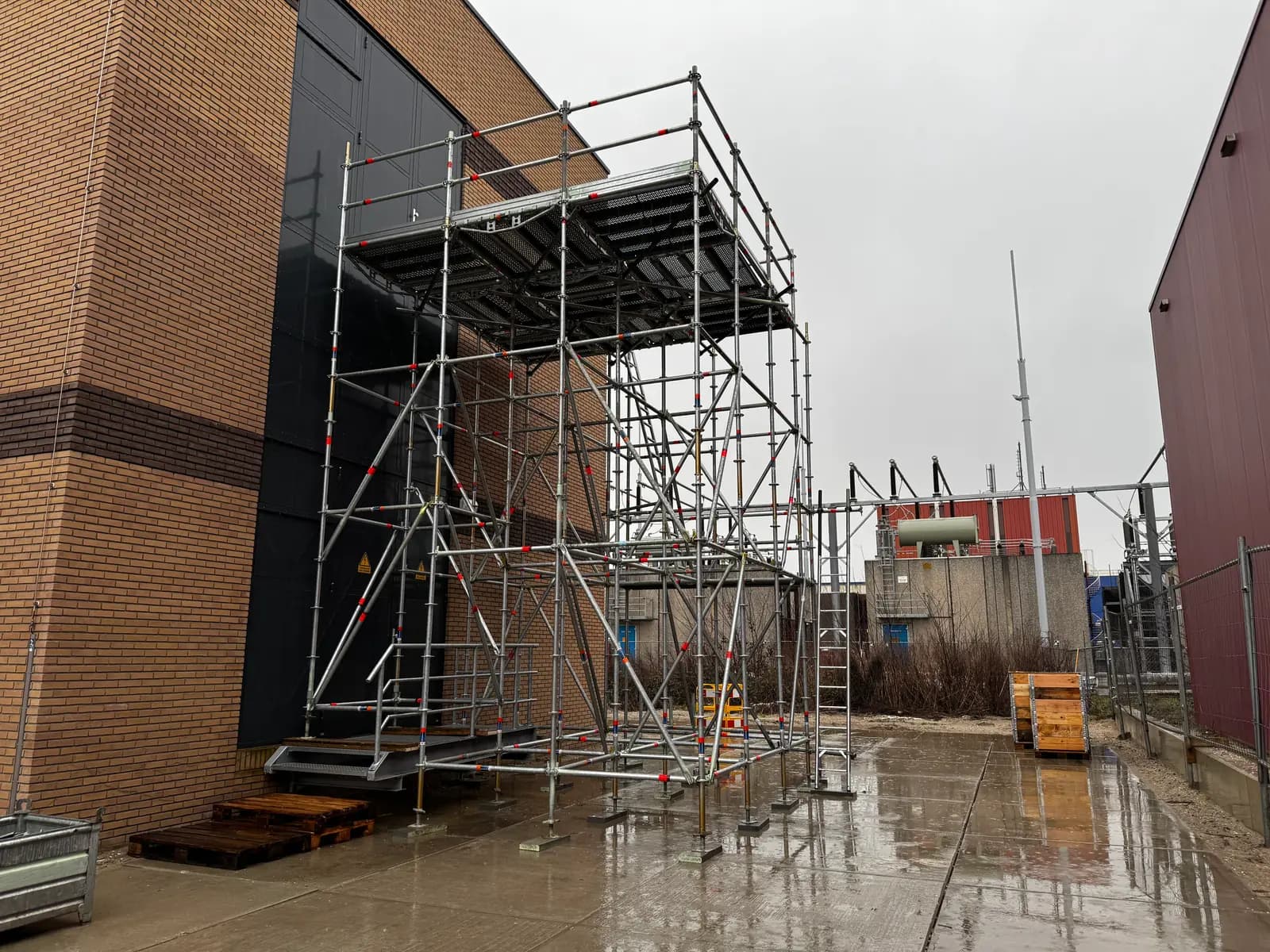 Vrijstaande steiger met werkplatform naast een industrieel gebouw