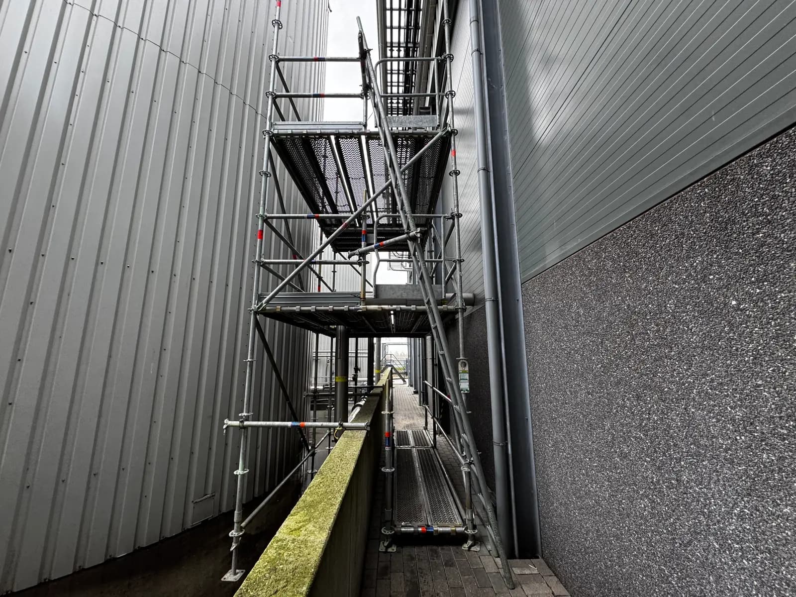 Steigerconstructie in een smalle doorgang tussen industriële gebouwen
