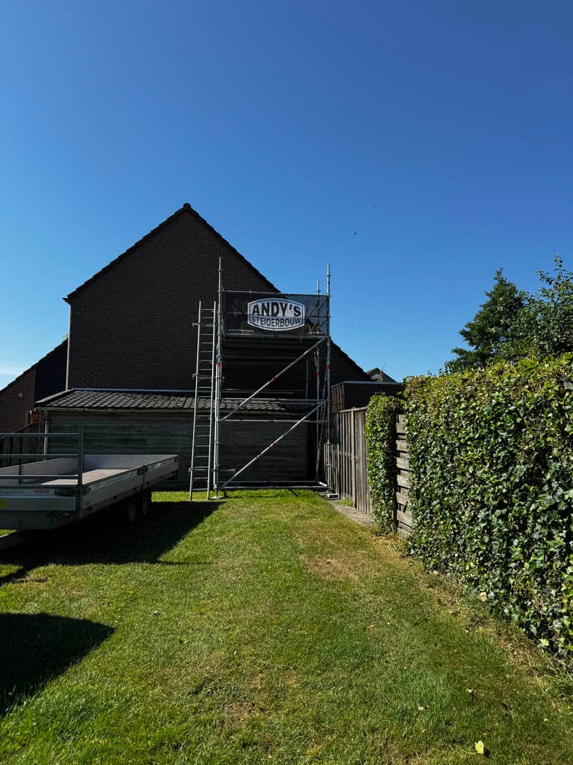 Gevelsteiger naast een woning met het bord van Andy’s Steigerbouw